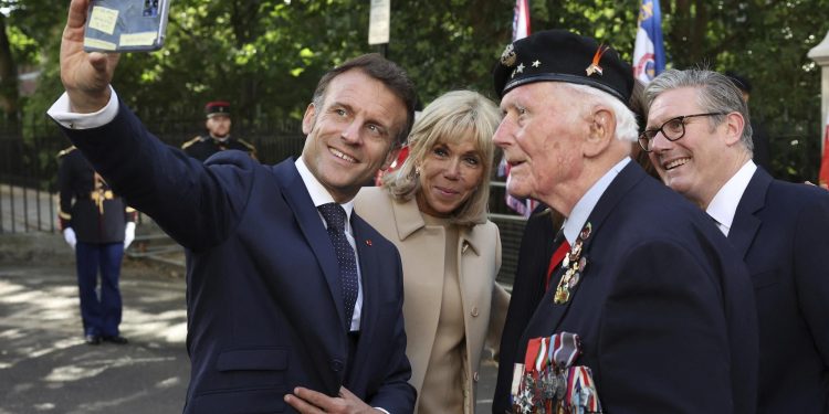 French President Emmanuel Macron takes a selfie with his wife Brigitte Macron, Britain's Prime Minister Keir Starmer and Veteran Eugenius Nead, as they attend a ceremony at the statue of former French President Charles de Gaulle, in London, Tuesday July 8, 2025. (Suzanne Plunkett/Pool Photo via AP)