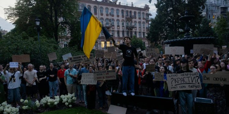 TOPSHOT - Protesters hold a national flag and placards during a demonstration calling for the Ukrainian president to veto a law passed by parliament that reduces the powers of Ukraine's National Anti-Corruption Bureau (NABU) and Specialised Anti-Corruption Prosecutor's Office (SAPO) in downtown Kyiv on July 22, 2025, amid the Russian invasion of Ukraine. Ukraine's parliament voted on July 22 to revoke the autonomy of the two anti-corruption agencies, a move that critics say will allow government meddling in high-profile graft cases. (Photo by Tetiana DZHAFAROVA / AFP) (Photo by TETIANA DZHAFAROVA/AFP via Getty Images)